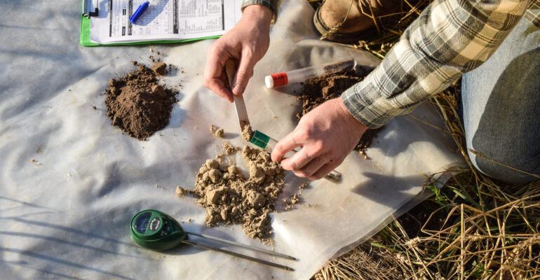 Closeup of agronomy specialist preparing soil samples for laboratory analysis outdoors. Professional farmer filling sample bag with material sampling at field. Environment research, soil certification